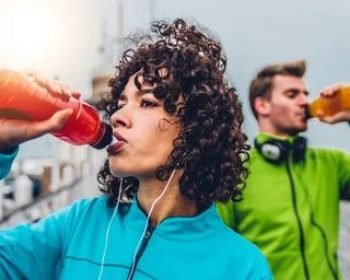 hispanic-runner-woman-drinking-energy alt="Una elegante botella negra para bebidas deportivas con tapón negro abatible".